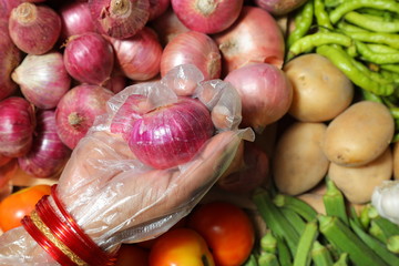 Indian Woman wearing gloves for hands consuming vegtables,indian market,asian vegetable market