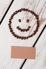 Coffee smiley and blank beige paper for copysapce. White wooden planks background.