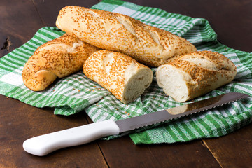 Sesame bread cut on cutting board with checkered cloth
