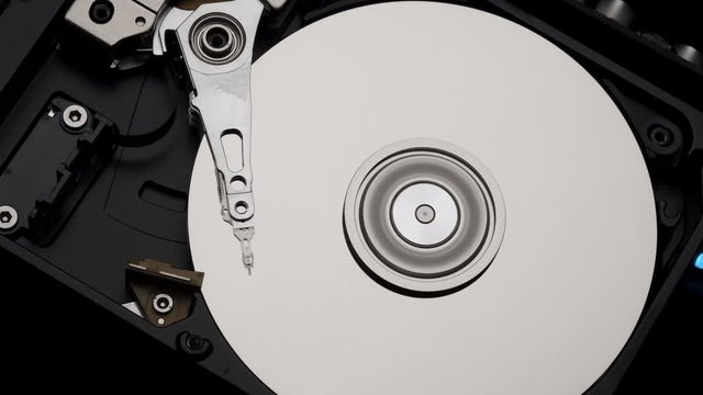 Macro, Close-Up of Computer Hard Disk Drive Spinning and Writing then Rotation Stop. Blue Lights Blinking. 4k 
