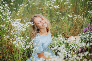 beautiful blonde girl in a field of daisies. wreath of wildflowers on his head. woman in a blue dress in a field of white flowers. charming girl with a bouquet of daisies. summer tender photo