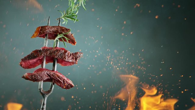 Close-up of delicious beef pieces on fork with falling salt and herbs, super slow motion, filmed on high speed cinematic camera at 1000 fps.