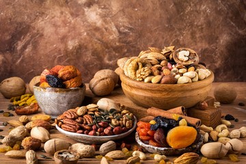 Composition from mix of dried fruits and nuts - symbols of judaic holiday Tu Bishvat. Brown background, space for text.