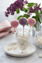 tasty cake pops in a glass with marshmallows on a background of lilac flowers. vertical image.