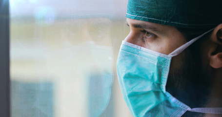 Dottore stanco guarda fuori dalla finestra del pronto soccorso