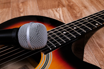 Microphone and guitar on a wooden background