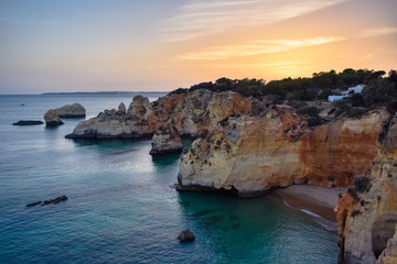 Small summer house on top of the cliffs, overlooking the sea, at sunset. Algarve, Portugal