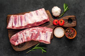raw pork ribs with spices on a cutting board on a stone background