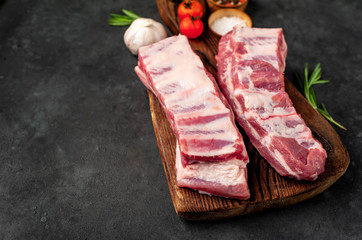 raw pork ribs with spices on a cutting board on a stone background with copy space for your text