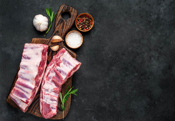 raw pork ribs with spices on a cutting board on a stone background with copy space for your text