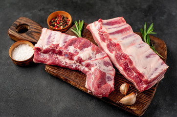 raw pork ribs with spices on a cutting board on a stone background