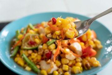 Close up Scoop Corn Salad with Salted Eggs or Tum Kwan Pod Kai Kem. Spicy food in Thailand.