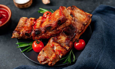 
Grilled pork ribs with spices on a plate on a stone background