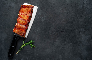 Grilled pork ribs with spices on a knife on a stone background with copy space for your text