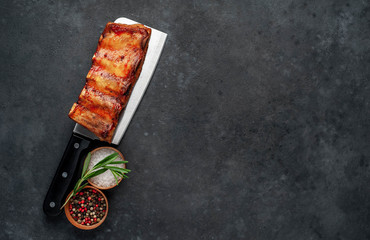 Grilled pork ribs with spices on a knife on a stone background with copy space for your text