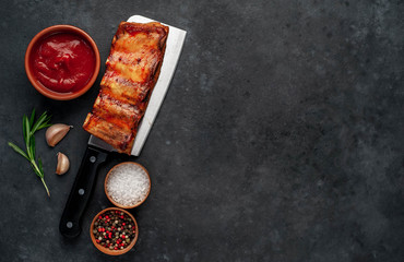 Grilled pork ribs with spices on a knife on a stone background with copy space for your text