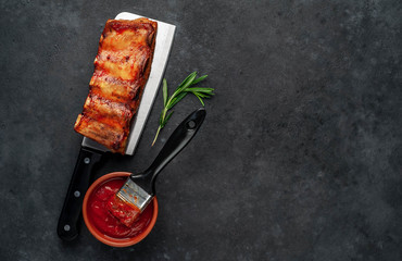 Grilled pork ribs with spices on a knife on a stone background with copy space for your text