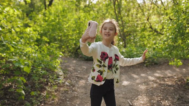 Girl pre-teen in the Park shoots a vlog on her smartphone.
