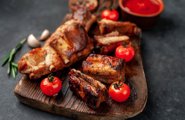 Grilled pork ribs with spices on a cutting board on a stone background