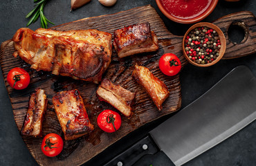 Grilled pork ribs with spices on a cutting board on a stone background