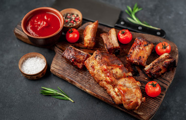 Grilled pork ribs with spices on a cutting board on a stone background