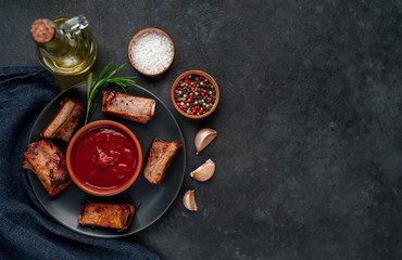 
Grilled pork ribs with spices on a plate on a stone background 
with copy space for your text