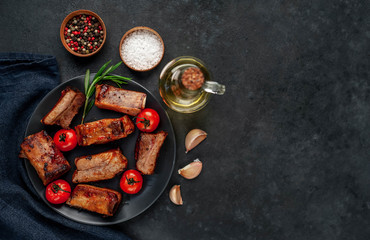 
Grilled pork ribs with spices on a plate on a stone background 
with copy space for your text