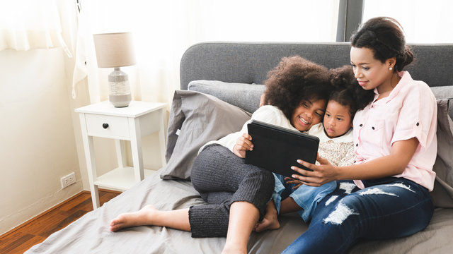 African American mum and daughter are watching the tablet relaxed in the house. Ideas about staying at home with family Teaching homework and relaxation