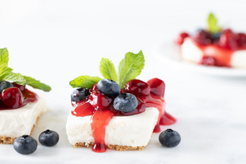 A close up view of a cherry cheesecake square with another one in soft focus in behind.