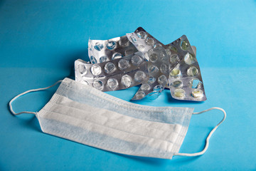 packaging from pills and medical mask on a blue background