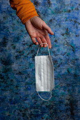 medical mask in a male hand on a blue background