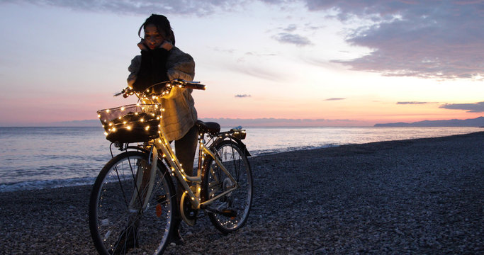 Ragazza si rilassa con la bicicletta in riva al mare durante il tramonto