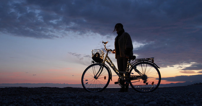 Ragazza si rilassa con la bicicletta in riva al mare durante il tramonto