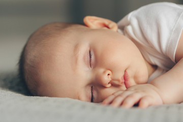 Close-up portrait of a beautiful sleeping baby boy on grey