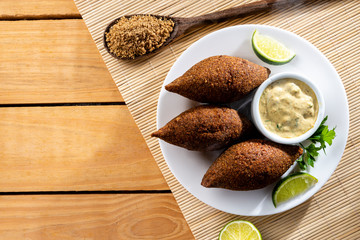 Delicious fried kibbeh served on a  plate on an wooden table, classic recipe. Flat lay.