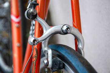 Fototapeta na wymiar Bicycle repair. Wheel and shiny axle of chrome steel of an old road bike closeup. Retro bike. Red iron fork. Quick Release.