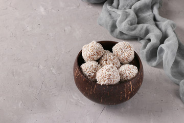 Energy balls of nuts and oatmeals with coconut flakes in coconut bowl on gray background, horizontal format, Copy space