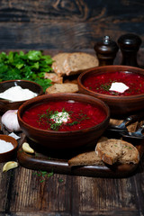 traditional russian dish borsch with sour cream and dill on wooden table, vertical