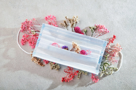 Medical mask and flowers. The concept of seasonal allergies, flu and spring quarantine