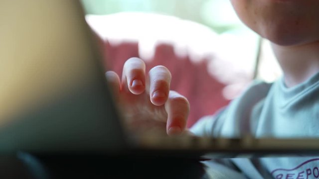 Close up of child’s hand on laptop  doing schoolwork at home