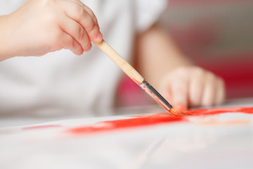 Cute happy little girl, adorable preschooler, painting with water color situng in a sunny white room at home or elementary school, creative young artist at work