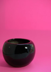 the bright pink background contrasts with the glossy black bowl