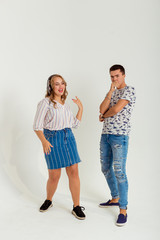 Fototapeta premium The girl dances and sings to music in headphones, and the guy looks at her with displeasure