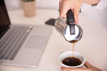 mano sirviendo café con el ordenador