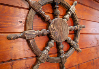 Fototapeta premium The background of the sea characters. Steering wheel of the ship on a wooden Board