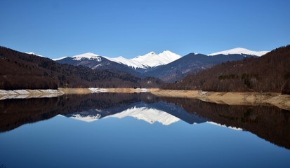 snowy mountains reflecting in the lake with blue sky