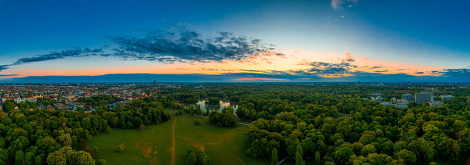 Munich, Bavaria. Panoramic aerial of a beautiful sunrise in the Englischer Garten, a popular park with dawn colors of the early morning of the famous german city.
