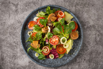 Vegetarian salad of leaves, tomatoes, pickled champignon mushrooms. Concept healthy food. Top view, copy space.
