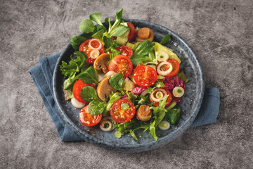 Vegetarian salad of leaves, tomatoes, pickled champignon mushrooms. Concept healthy food. Top view, copy space.