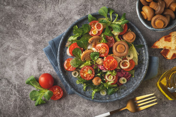 Vegetarian salad of leaves, tomatoes, pickled champignon mushrooms. Concept healthy food. Top view, copy space.